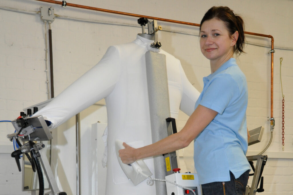Mitarbeiterin von Masterdress bedient eine professionelle Finish-Maschine für Arbeitskleidung