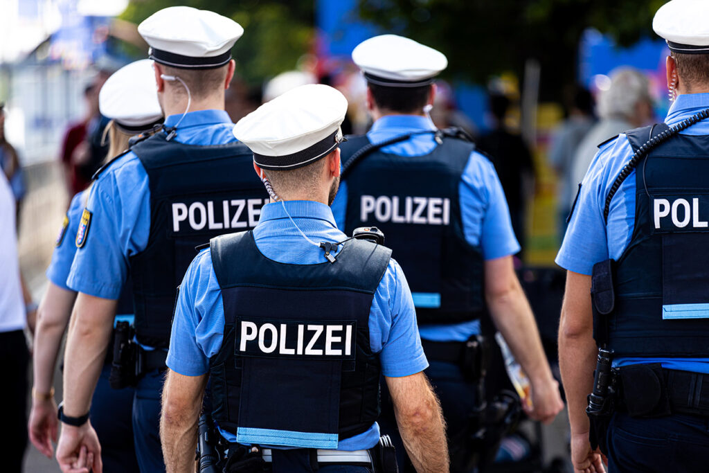 Gruppe von Polizei-Beamt:innen in blauer Uniform, von hinten im Einsatzbereich – Beispiel für Behördenkleidung