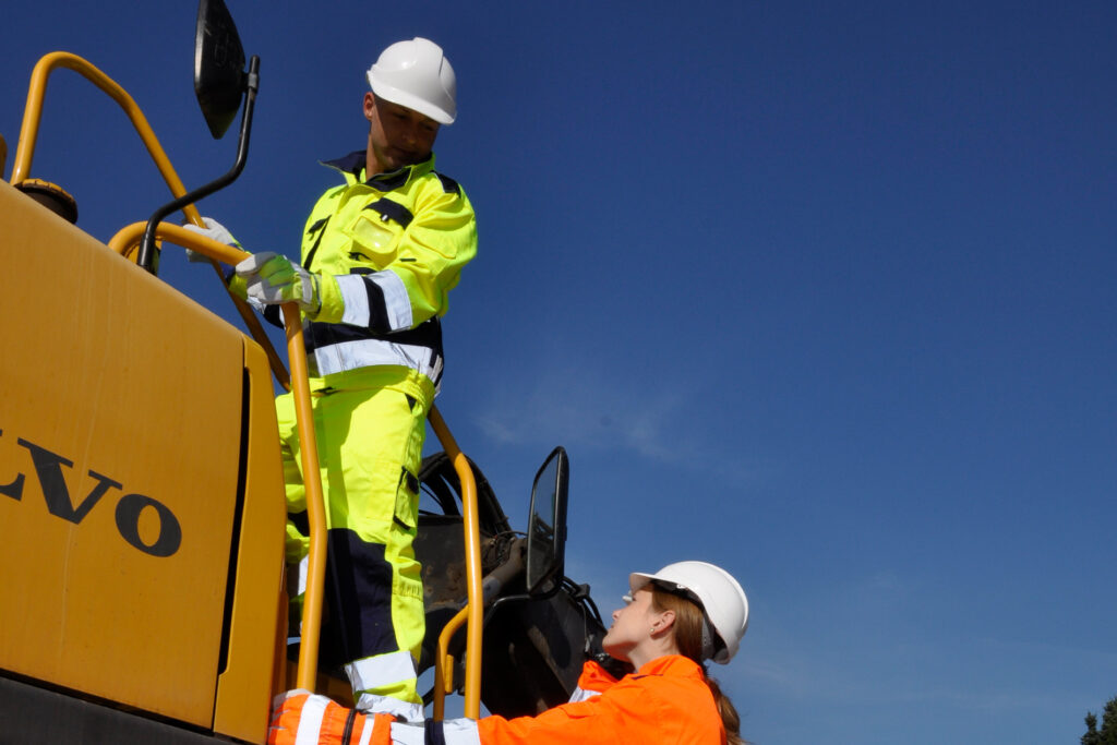 Bauarbeiter in fluoreszierender Sicherheitskleidung und Schutzhelmen auf einer Baustelle